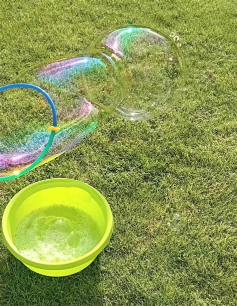 Vaikas pūčia muilo burbulus su dažais ant popieriaus