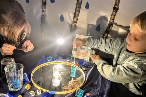 Vaikai tyrinėja vandenį su padidinimo stiklu