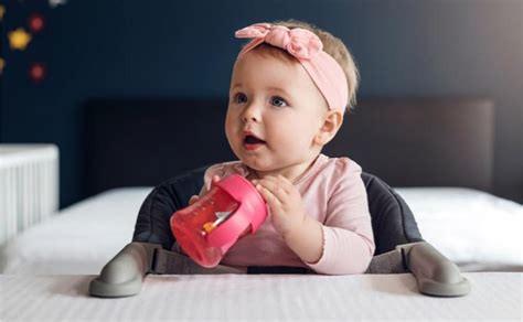 Kūdikis laiko gertuvę su rankenėlėmis