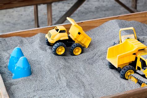 Vaiko rankos žaidžia su smėliu smėlio dėžėje